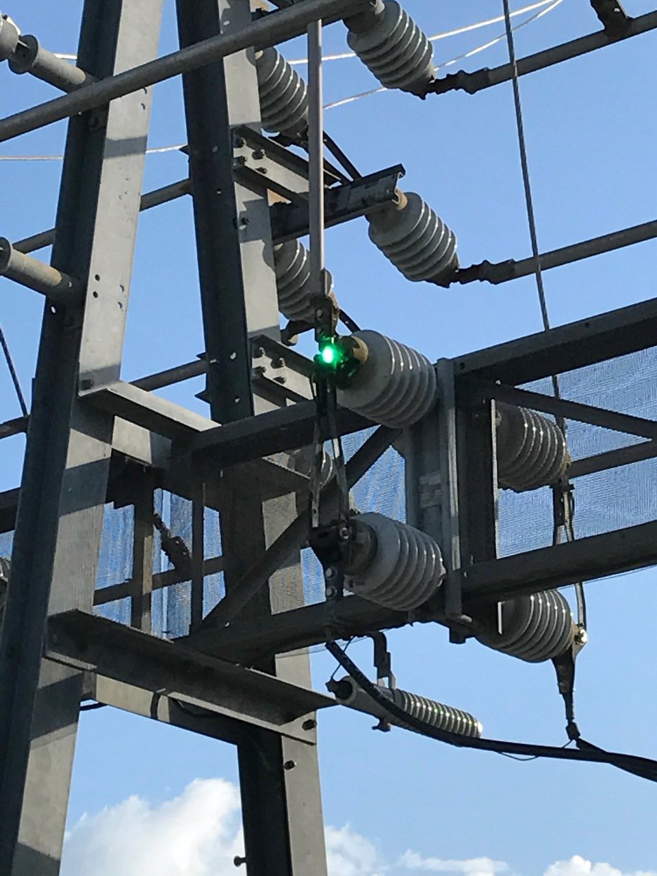 A blade switch on a substation structure with a bright arc at its jaw